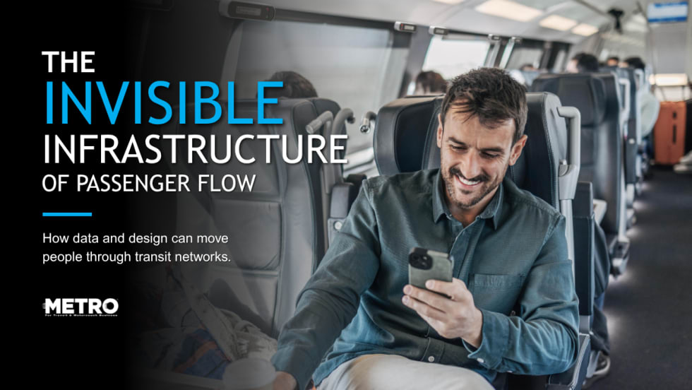 A man sits in a passenger rail seat and looks at his phone.