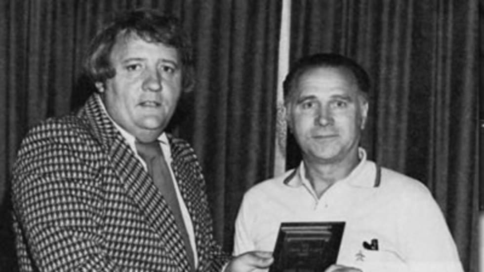 two men pose with an award