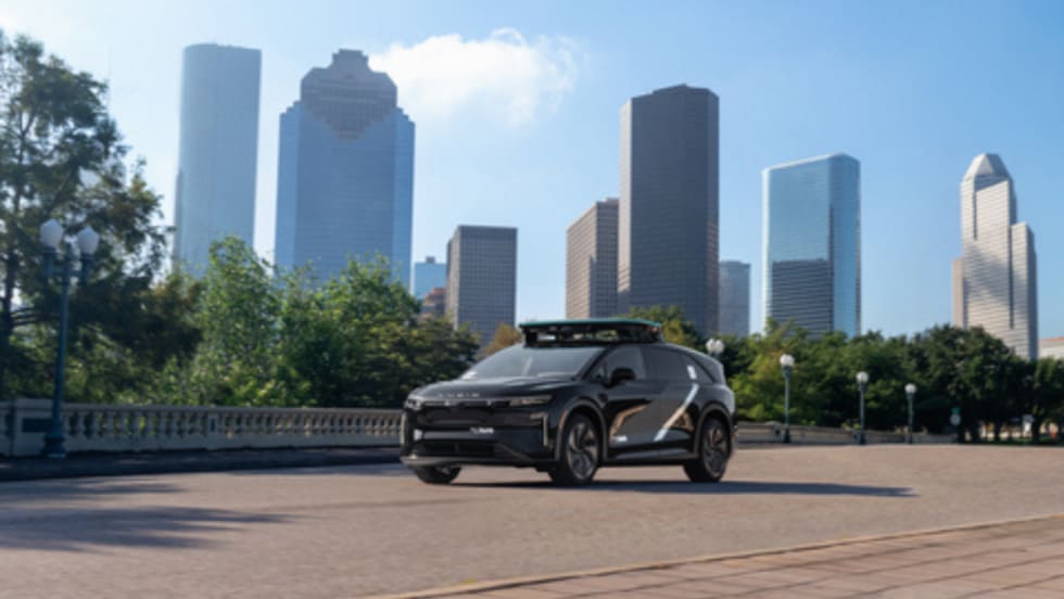 A Lucid Gravity robotaxi parked in front of the Houston skyline.