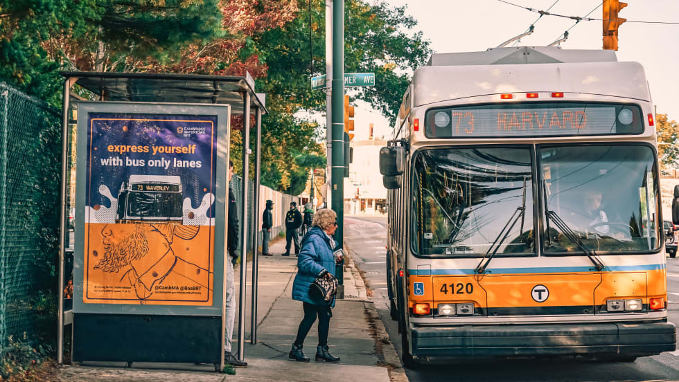 An MBTA bus with a passenger boarding at shelter. 