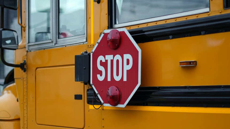 The side of a school bus with a retracted stop signal.