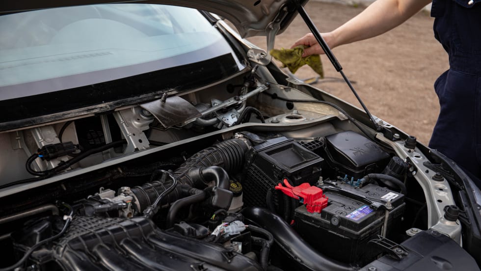 Photo of male mechanic next to car with open hood