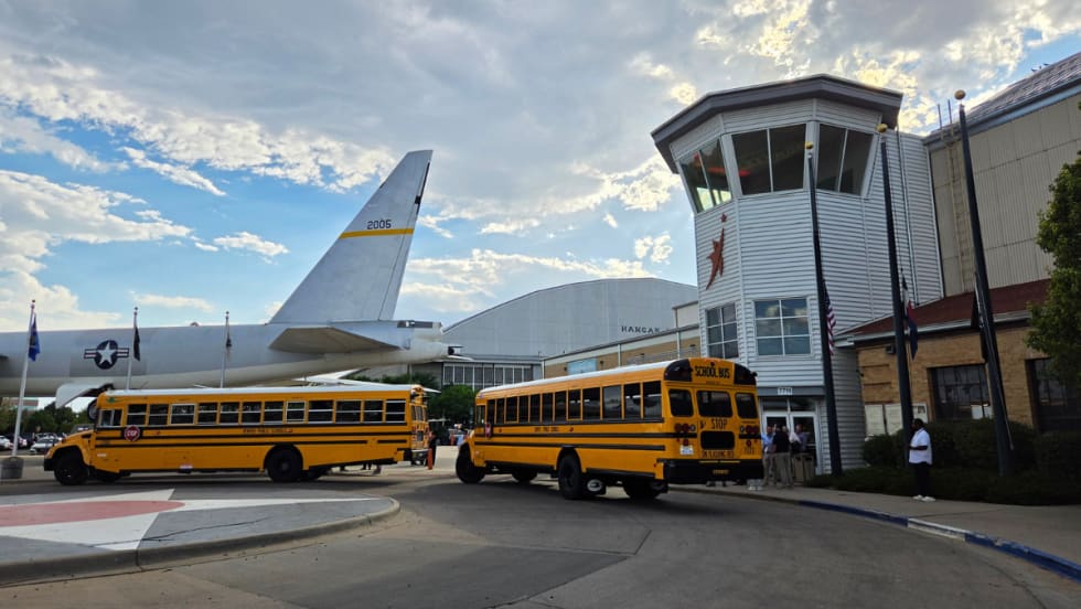 Two school buses parked in front of the Wings Over the Rockies Air & Space Museum in Denver.