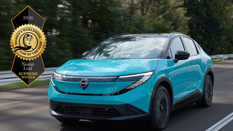 blue Nissan Leaf driving down the road with a badge for winning Women's Worldwide Car of the Year
