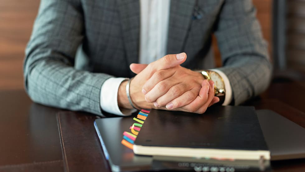 Photo of businessman's hands resting on files on a desk