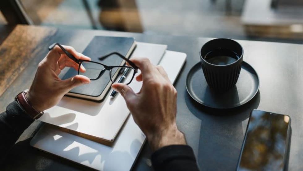Photo of businessman's hands holding eyeglasses at a desk