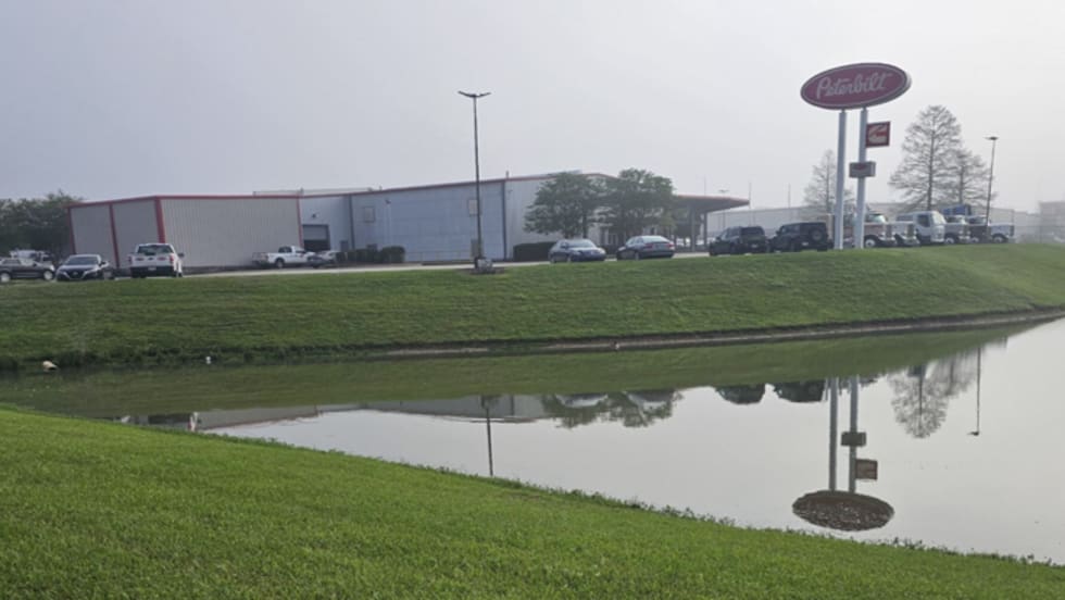 Photo of truck dealership with pond in foreground 