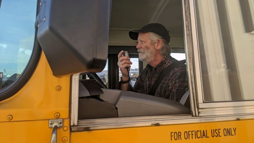 a man drives a school bus and talks through the radio