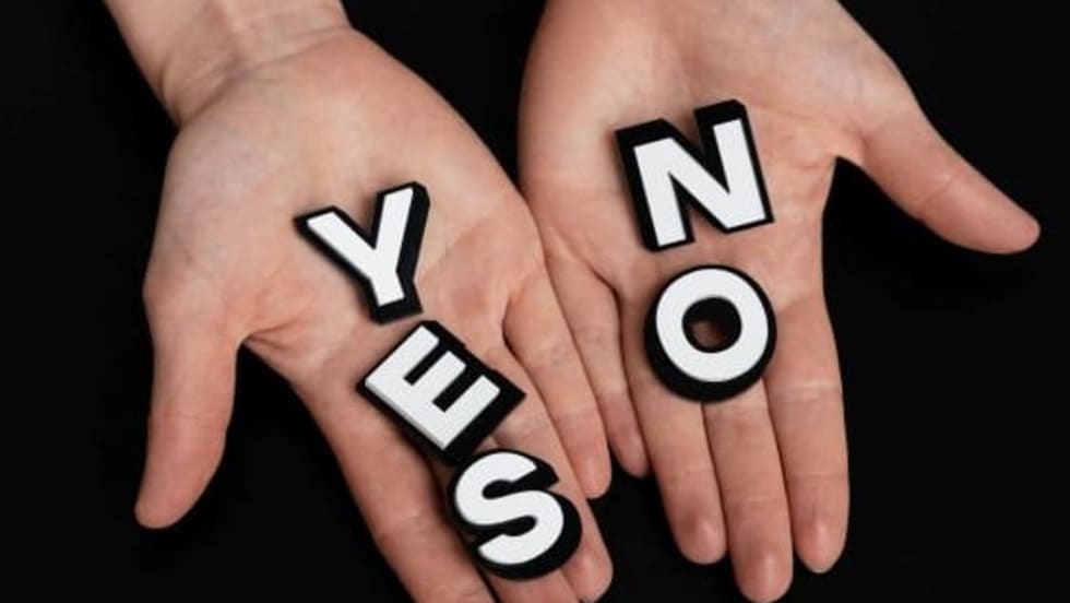 Image of two human hands, one holding the word yes, the other the word no