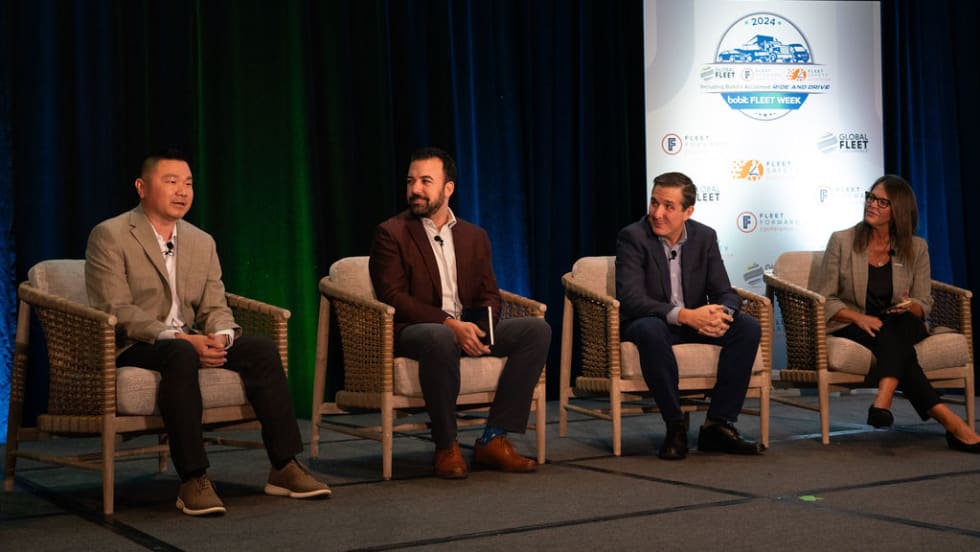 Four people sitting on stage doing presentation. 