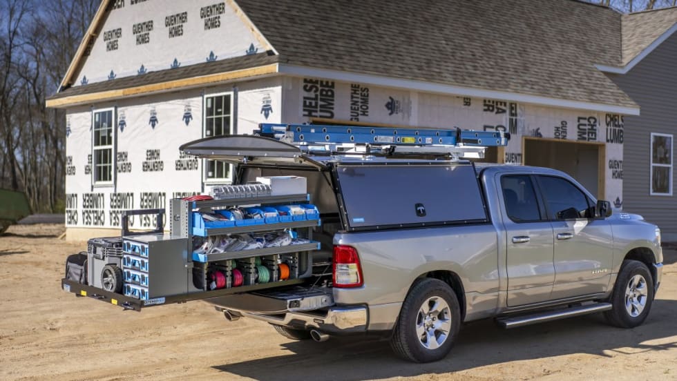 An upfitted truck with ladder rack and storage on a construction site.