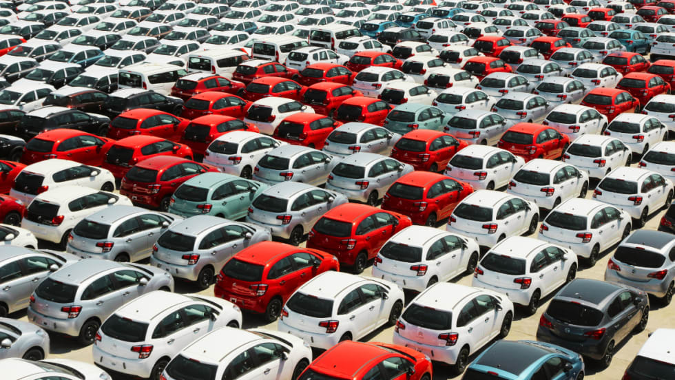 A car lot filled with red, gray, and white cars.