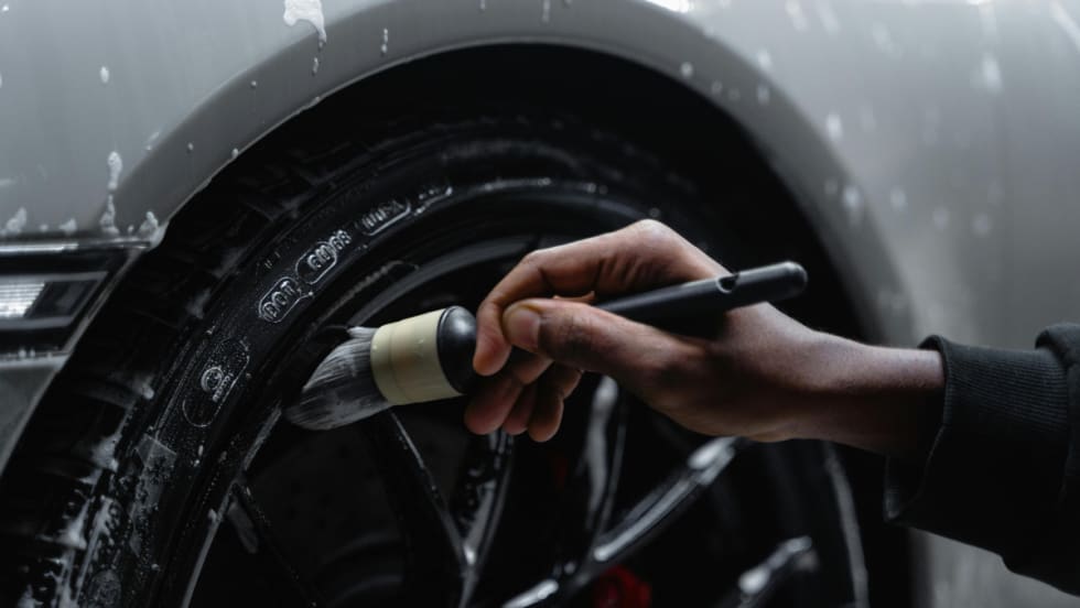 Close up shot of someone cleaning the crevices in a hub cap and tire.