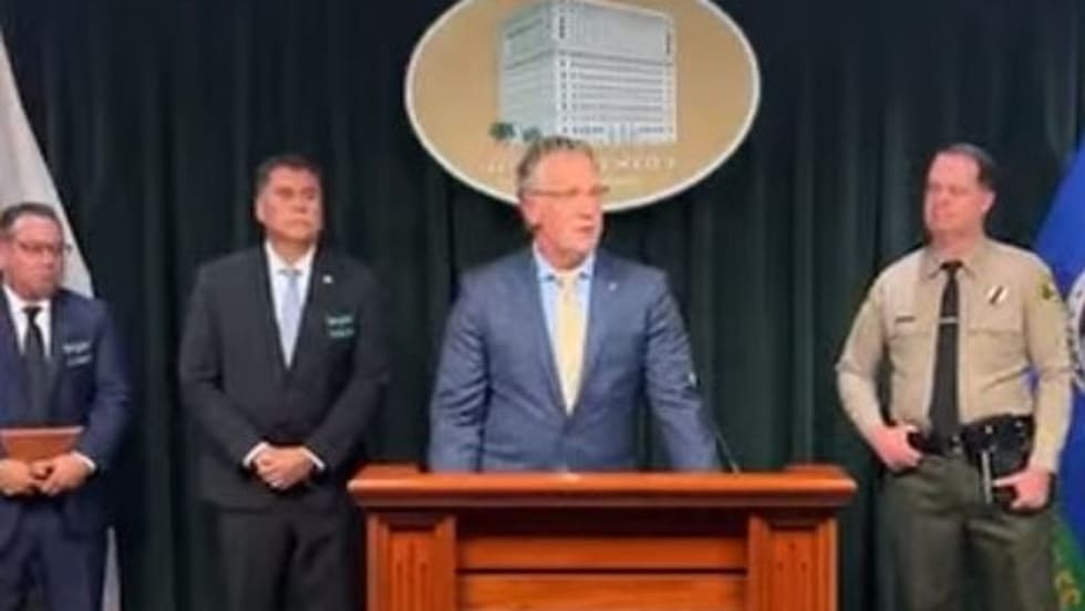 Law enforcement press conference with officials at podium with sheriff's badge