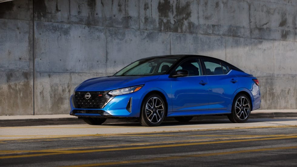 A cobalt blue 2025 Nissan Sentra parked on the side of the road underneath an overpass.