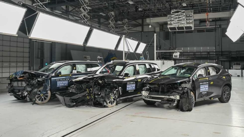 Three wrecked midsize SUVs in a crash testing room.