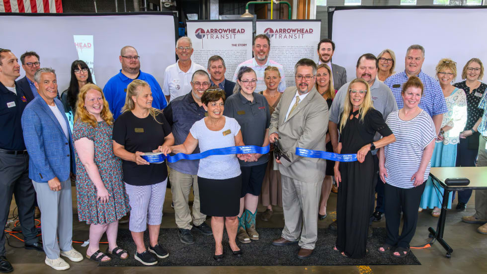 Business and community members pose during a ribbon cutting.