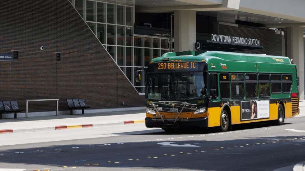 A green and yellow King County Metro bus outside a station.