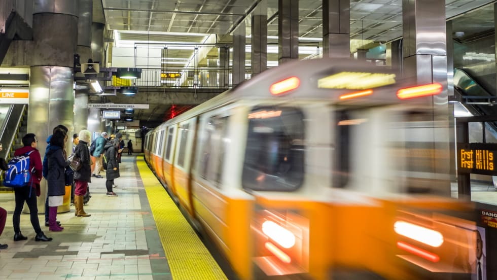 An MBTA Orange Line passenger train driving through a station.