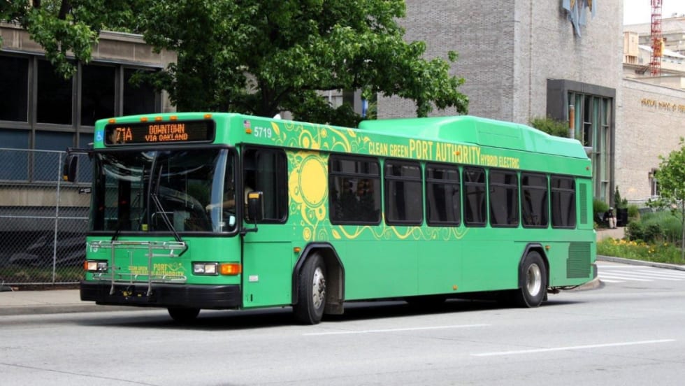 A bright green PRT bus on a city street.