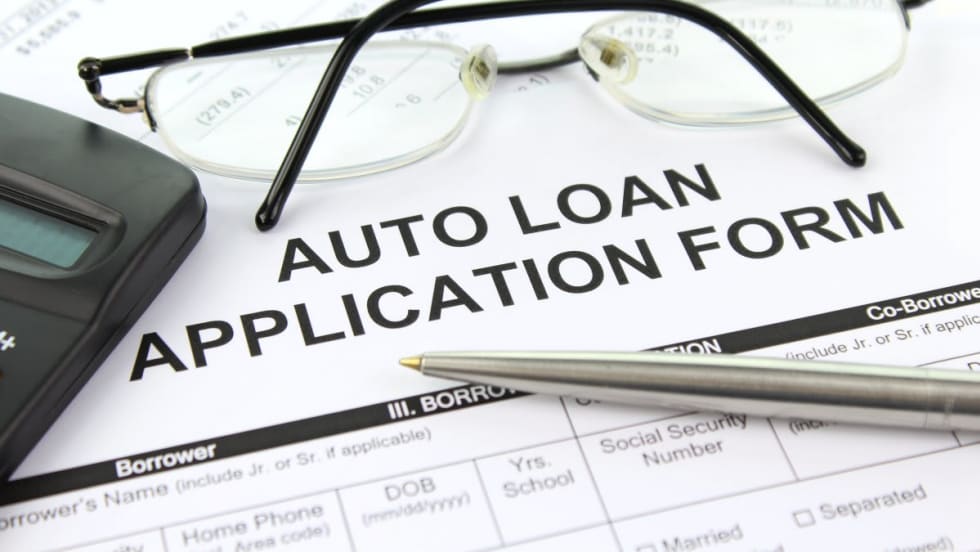 Photo of auto loan application form with eyeglasses, pen and calculator on top of it