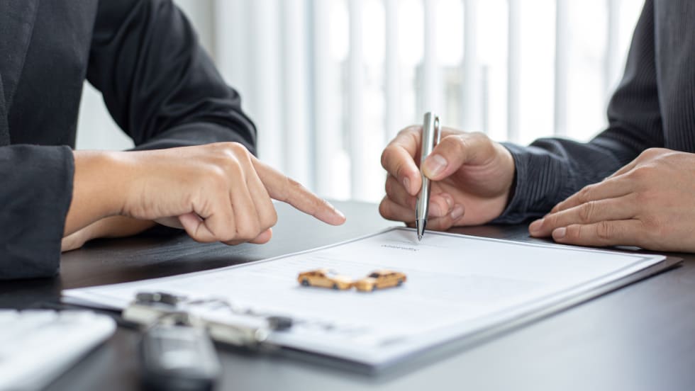 Two people signing auto insurance paperwork