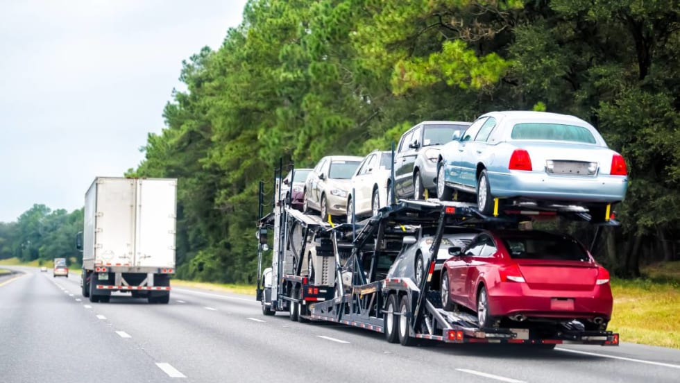 A double-decker stinger auto transporter driving down the freeway.
