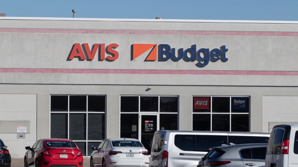 Rental cars lined up in front of an Avis-Budget storefront outlet.