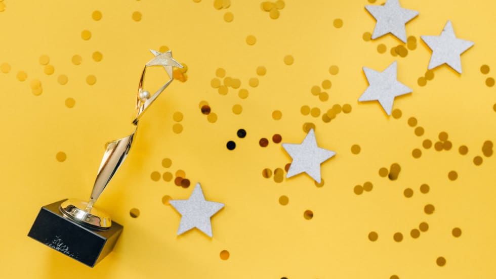 yellow background with awards trophy and confetti
