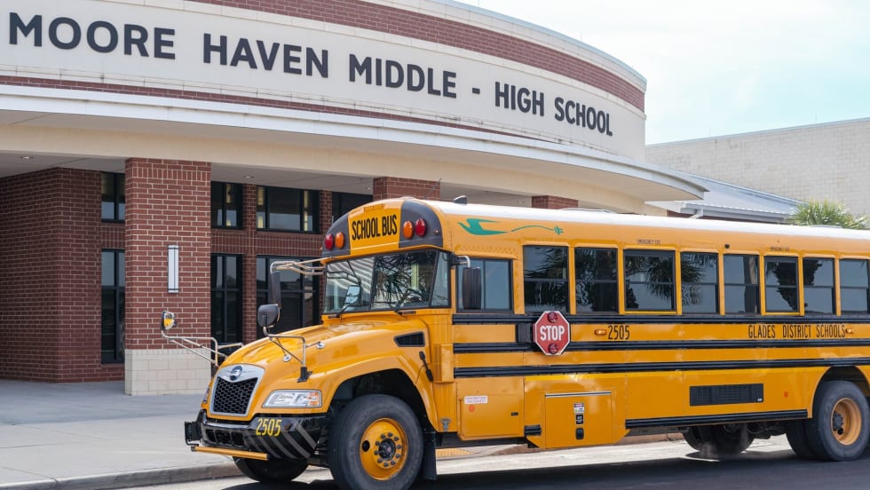 an electric school bus in front of a school