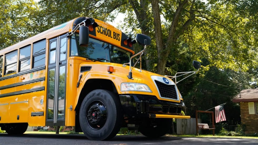 a school bus on a road with trees in the background