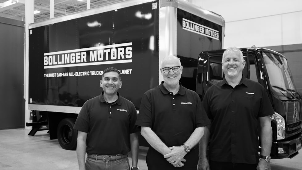 Siva Kumar, James Taylor, and Bryan Chambers pose in a black and white photo in front of a Bollinger all-electric commercial truck.