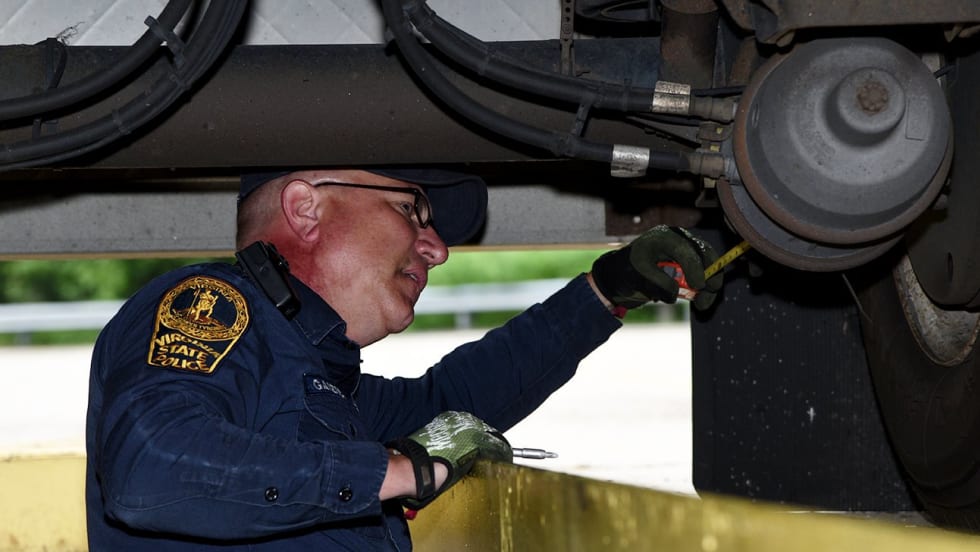 CVSA inspector looking at brakes underneath truck