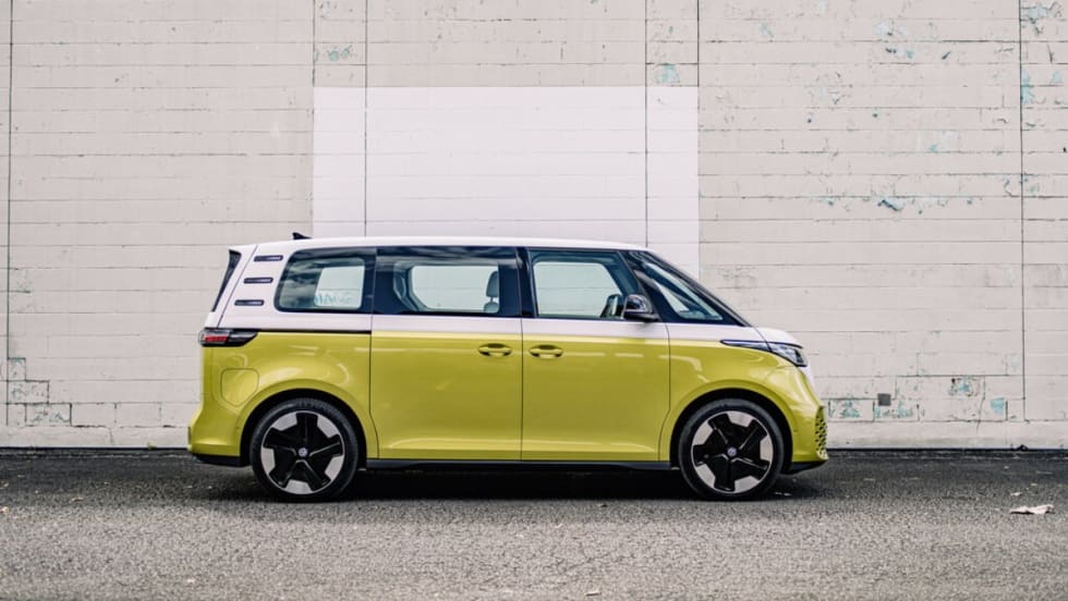 An electric green Volkswagen ID. Buzz parked in front of a white brick wall. 