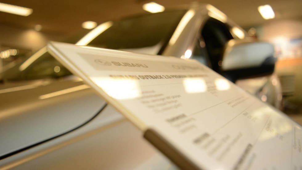 Sales board in front of a car inside a dealership showroom floor.