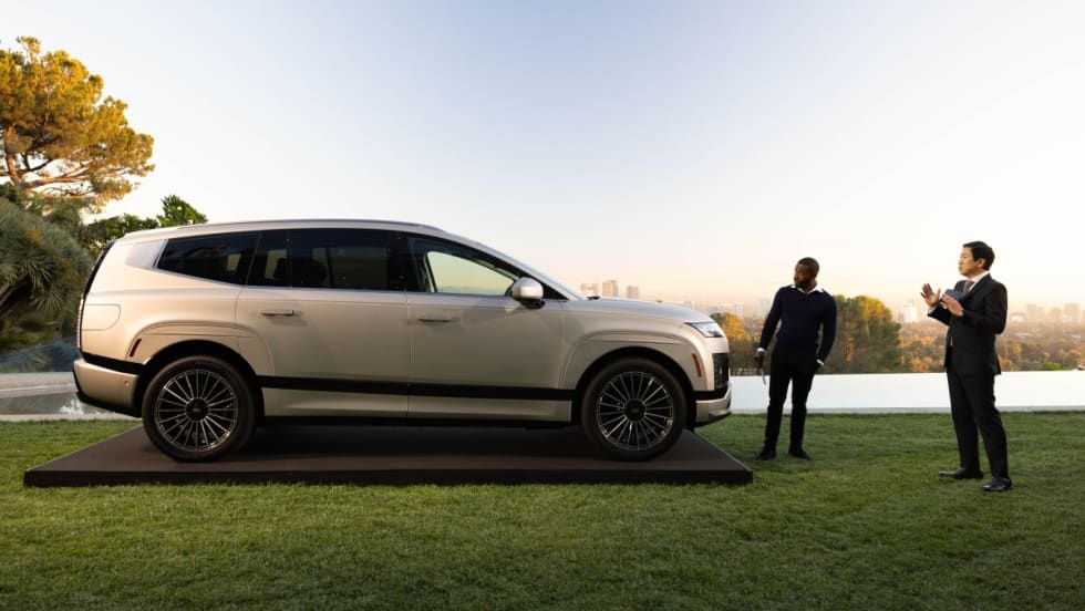 An image of a new Hyundai Ioniq 9 parked on a green lawn with two business men standing off to the right.