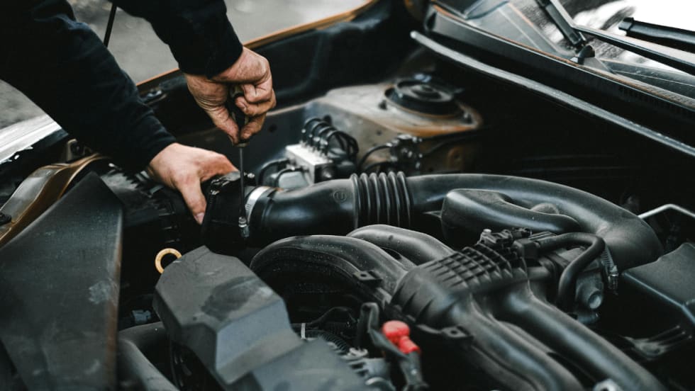 The hands of an auto mechanic checking the engine of a car.