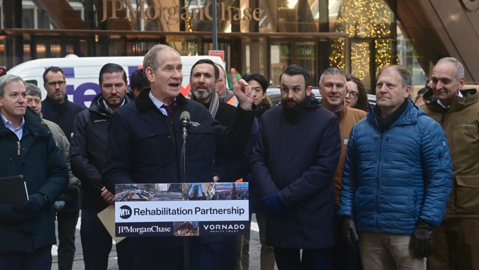 MTA Chair and CEO Janno Lieber stands at a podium in front of a crowd outside the JPMorganChase building.