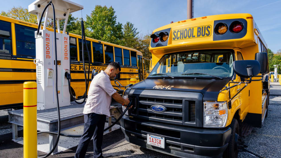 A man connecting a Zenobē charger to a school bus.