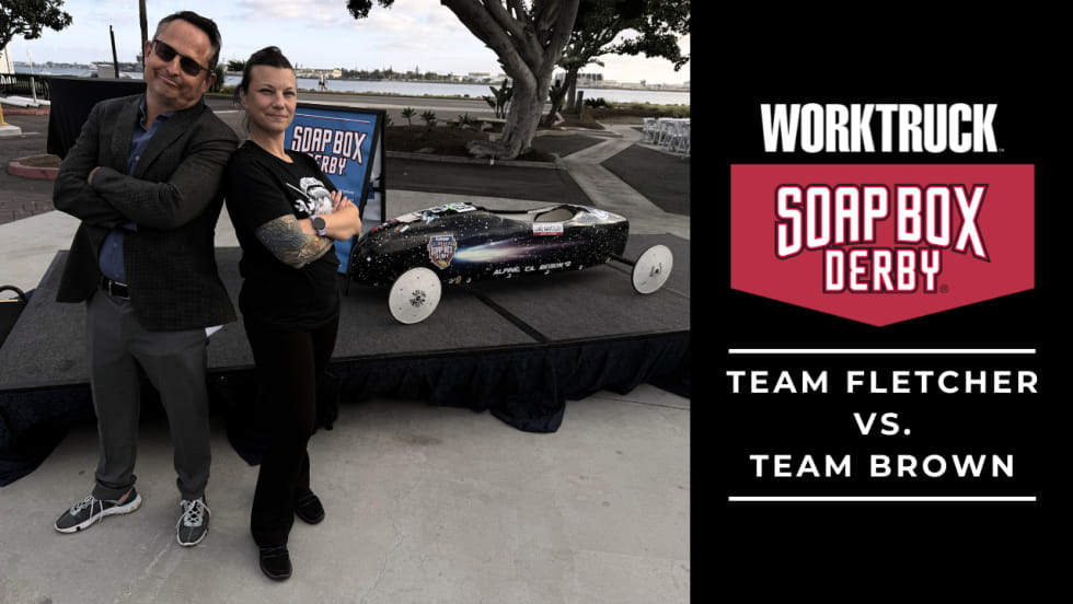 Chris Brown and Lauren Fletcher stand in front of Soap Box Derby race car for promotion of Soap Box Derby Corporate Challenge. 