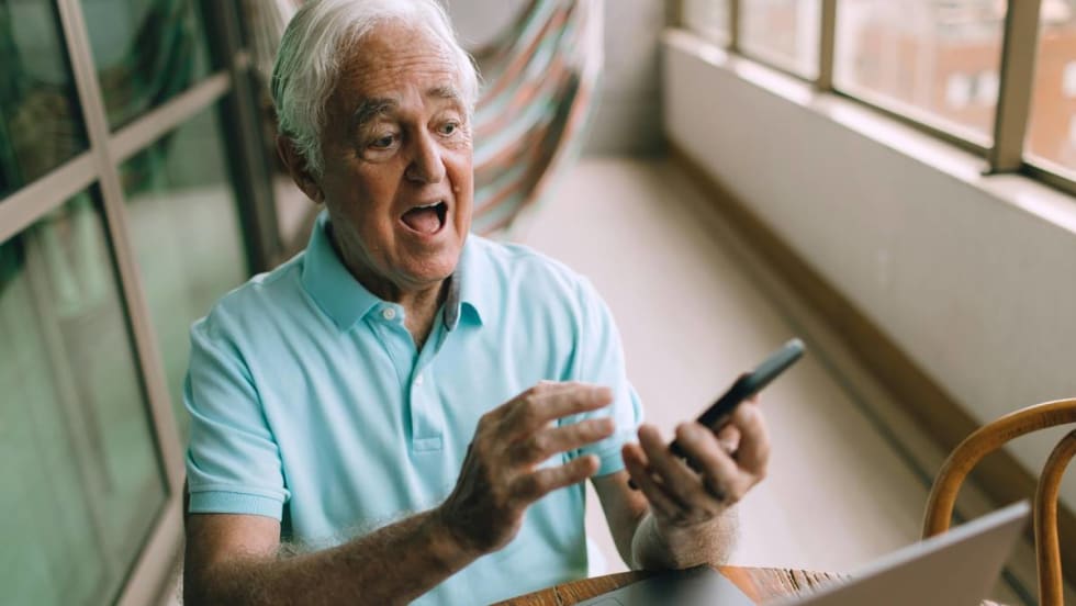 A thrilled older gentleman sees a valued used vehicle for sale on a digital device.