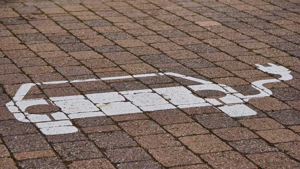 White drawing  on brick surface of car with a charger cable sticking out of it