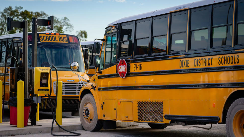 two school buses park in ev charging spots