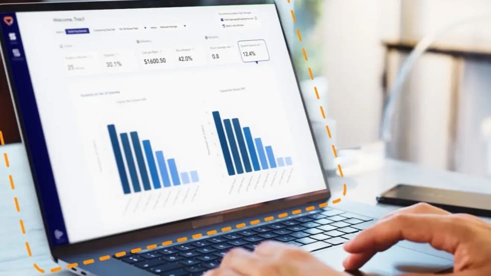 Laptop displaying HopSkipDrive RouteWise AI transportation analytics dashboard with charts and routing performance data for school district operations.