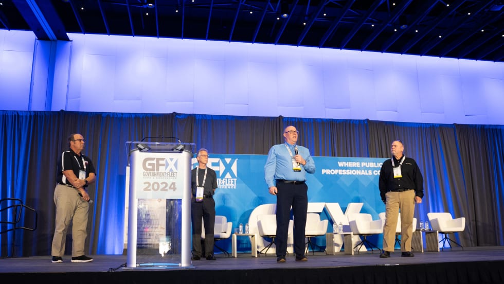 Sam Lamerato from the city of Troy, Michigan; Jeff Tews, retired from the city of Milwaukee, Wisconsin; Kevin Schlangen from Dakota County, Minnesota; and Danny Breshear from AssetWorks stand onstage 