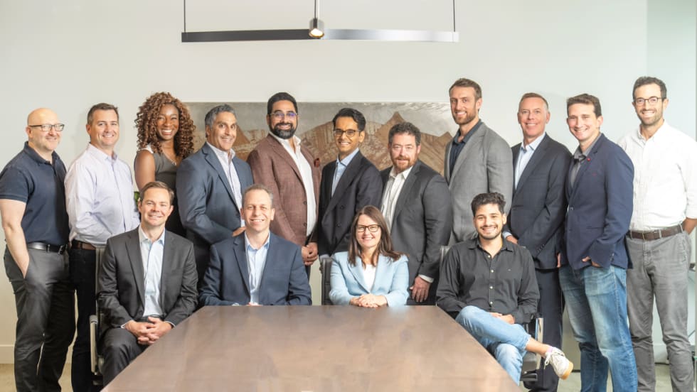 Executives pose around boardroom table. 