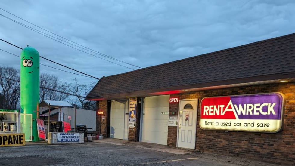 Inflatable green pop-up tank next to car rental outlet.