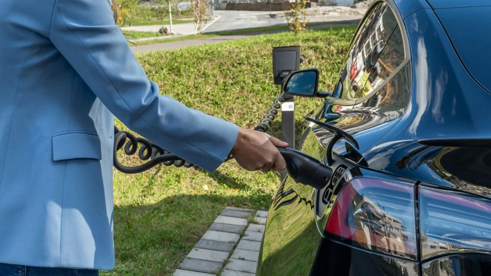 person outside plugging in electric vehicle to charge