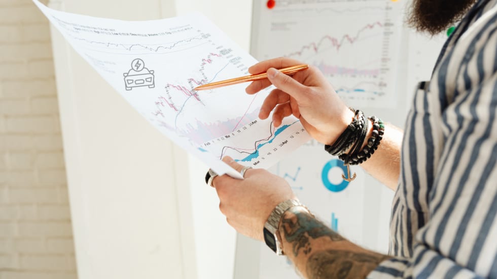 man holding up sales report and pointing with pencil