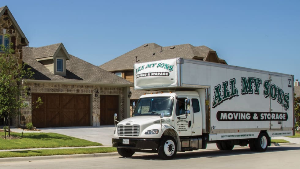An All My Sons Moving & Storage truck outside a residential home in a neighborhood.